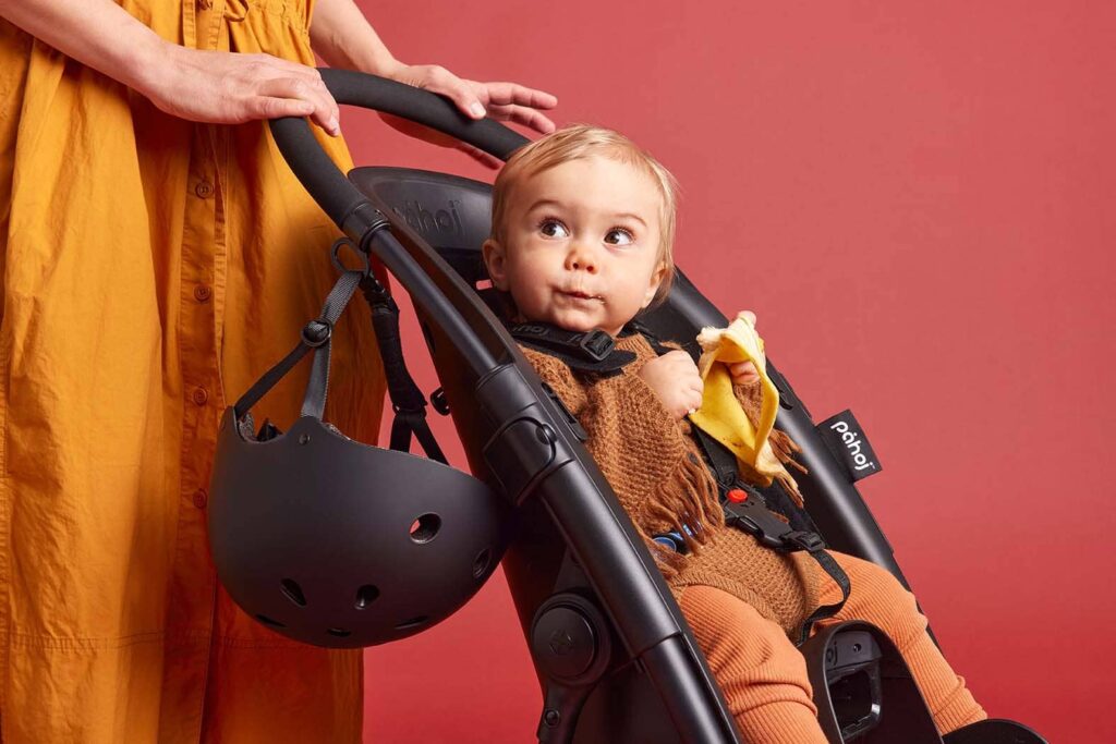 Product image for Påhoj. A toddler is sitting in the "påhoj" product that can be used as a stroller and be put on a bike