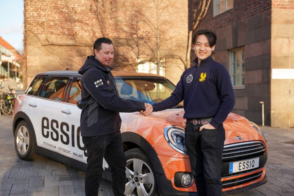 Electromobility Consultant manager Simon Laestander shaking hands with a KTH Formula Student in front of an ESSIQ branded car that KTH gets to borrow.